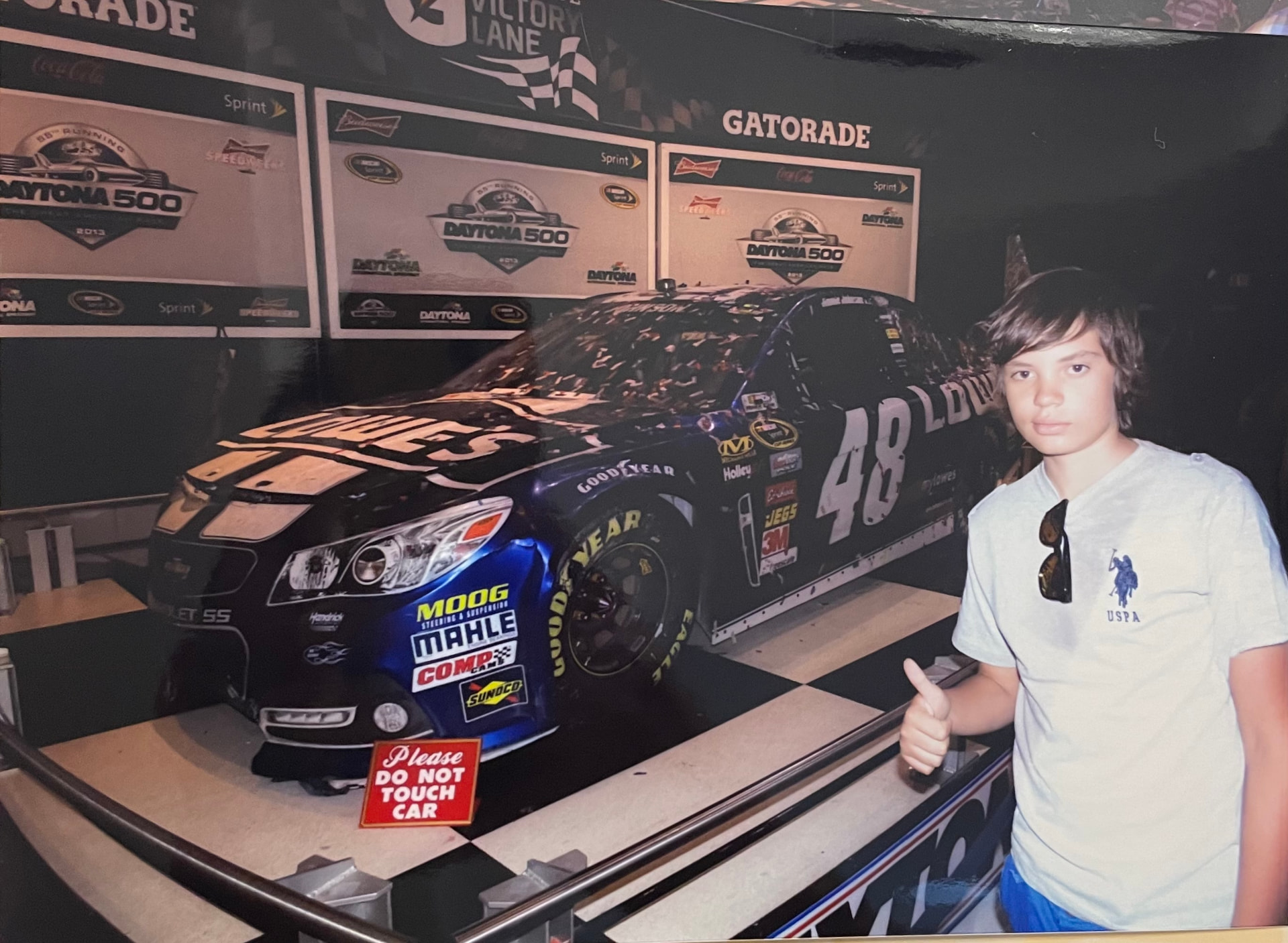 De chico en Daytona, frente al auto de NASCAR